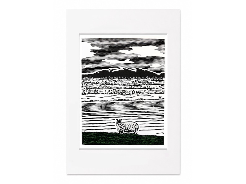 May include: Black and white landscape print featuring a sheep in a field, with a mountain range in the background. The artwork is framed in a white mat. The print depicts a rural scene with a detailed, textured style.