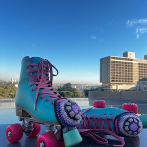Peut inclure: Une paire de patins à roulettes turquoise avec des lacets et des roues roses. Les patins ont un design rétro, avec une botte montante et un châssis en métal. Des protège-orteils en crochet dans les tons violets et beiges ajoutent une touche décorative.