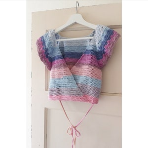 May include: A crocheted top with a rainbow striped pattern and short sleeves. The top has a wrap style and ties at the front.