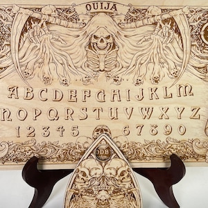 Ouija board with demons and skulls engraved on wood , wooden spirit board with planchette in gothic style with reaper pulling out souls