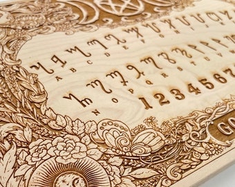 May include: A wooden Ouija board with a floral design and the letters of the alphabet, numbers, and the words "YES" and "GOODBY" engraved on the surface.