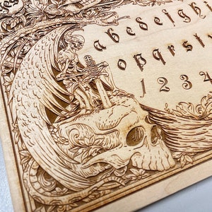 Ouija board with demons and skulls engraved on wood , wooden spirit board in gothic style with  demons planchette