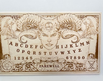 May include: A wooden Ouija board with a demonic face in the center, surrounded by the alphabet, numbers, and the words "YES", "NO", and "FAREWELL".