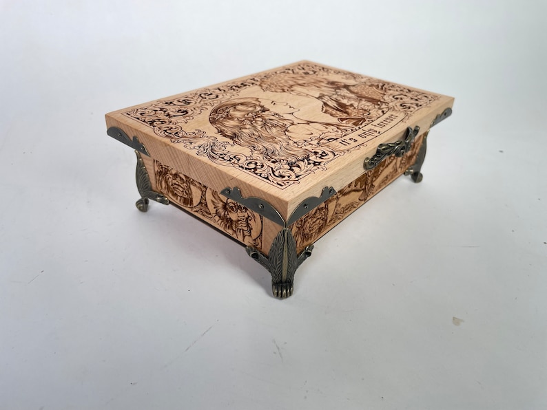 May include: A wooden box with a hinged lid and ornate metal accents. The lid features a woodburned image of two people with the text "It's a good life".