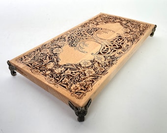 Puede incluir: Una bandeja de madera con un diseño de árbol de la vida grabado con láser y el texto "As Above So Below". La bandeja tiene cuatro patas metálicas decorativas.