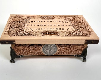 May include: A wooden Ouija board with a skull and crossbones design. The board has a black and white alphabet, numbers 1-9 and 0, and the word "Goodbye".