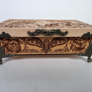 May include: A wooden box with a hinged lid and ornate metal accents. The box is decorated with a wood-burned design featuring an owl, a creature with a large nose, and the text "It's only forever".