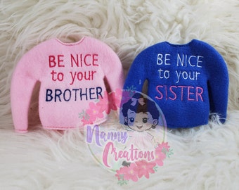May include: Two elf-sized sweaters, one pink and one blue, with the text "Be nice to your brother" and "Be nice to your sister" embroidered on them.
