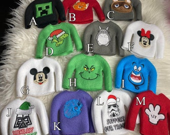 Puede incluir: Colección de pequeños suéteres, cada uno con un diseño diferente. Incluye un suéter negro con un bloque de Minecraft verde, un suéter rojo con un zorro y un suéter gris con un mapache.