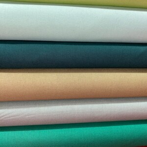 May include: Five rolls of fabric in different colors, including light blue, teal, beige, dark green, and light green.