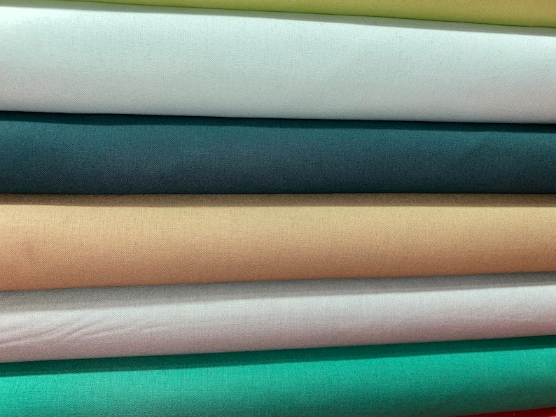 May include: Five rolls of fabric in different colors, including light blue, teal, beige, dark green, and light green.