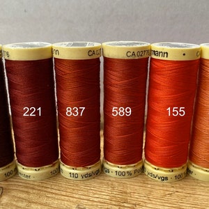 May include: Six spools of thread in various shades of orange and brown. The spools are labeled with numbers: 230, 221, 837, 589, 155, and 895.
