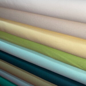 May include: A stack of fabric rolls in various colors, including beige, yellow, green, blue, teal, and brown.