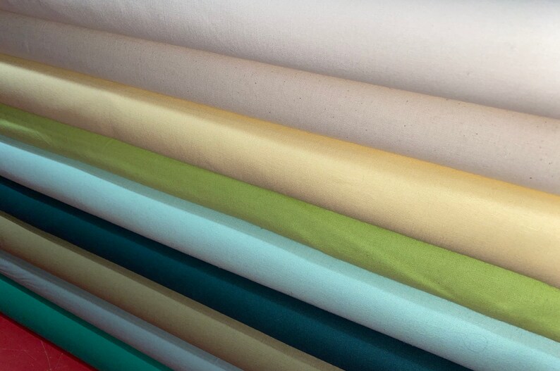 May include: A stack of fabric rolls in various colors, including beige, yellow, green, blue, teal, and brown.