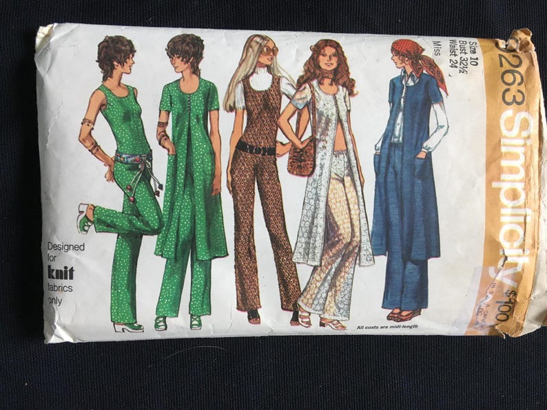 May include: Vintage Simplicity sewing pattern envelope showing illustrations of women's clothing designs. The designs include jumpsuits, dresses, and long coats. The envelope is cream-coloured with text and illustrations in various colours. The text reads "Designed for knit fabrics only."