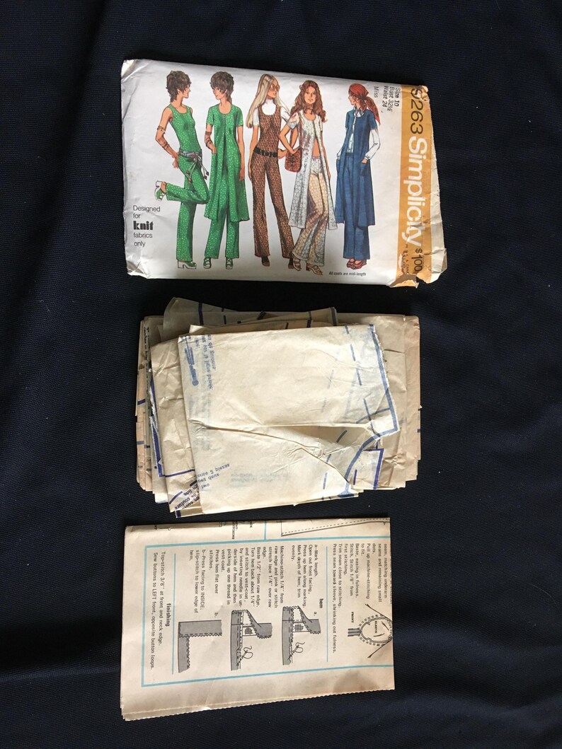 May include: A vintage Simplicity sewing pattern packet featuring illustrations of women's clothing designs. The packet includes pattern pieces and instructions. The design is for knit fabrics. The packet is labelled "$263 Simplicity".