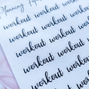 Op de afbeelding: Een vel wit papier met meerdere transparante stickers waarop in zwarte cursieve letters "workout" staat.