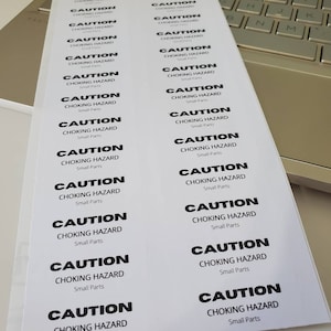 May include: A sheet of white stickers with the text "CAUTION CHOKING HAZARD Small Parts" repeated multiple times.