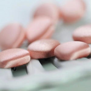 May include: A close-up shot of several small, oval, light pink cosmetic puffs. The puffs have a soft, textured appearance and are arranged on a light-coloured surface. The image is slightly out of focus, with some puffs blurred in the background.