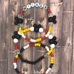 May include: Three beaded bracelets with Mickey Mouse heads and the word "MICKEY" spelled out in silver beads. The bracelets are red, white, yellow, and black.