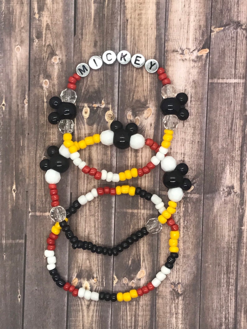 May include: Three beaded bracelets with Mickey Mouse heads and the word "MICKEY" spelled out in silver beads. The bracelets are red, white, yellow, and black.