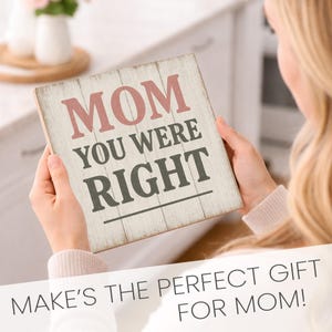 May include: A square wooden sign with the words "MOM YOU WERE RIGHT" in pink and gray lettering. The sign has a distressed, whitewashed appearance and is held by a person. The sign is a gift for mothers.