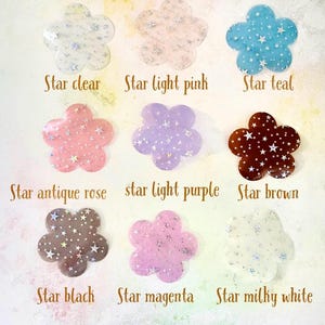 May include: Nine different colors of star-shaped flower embellishments. The colors are clear, light pink, teal, antique rose, light purple, brown, black, magenta, and milky white.