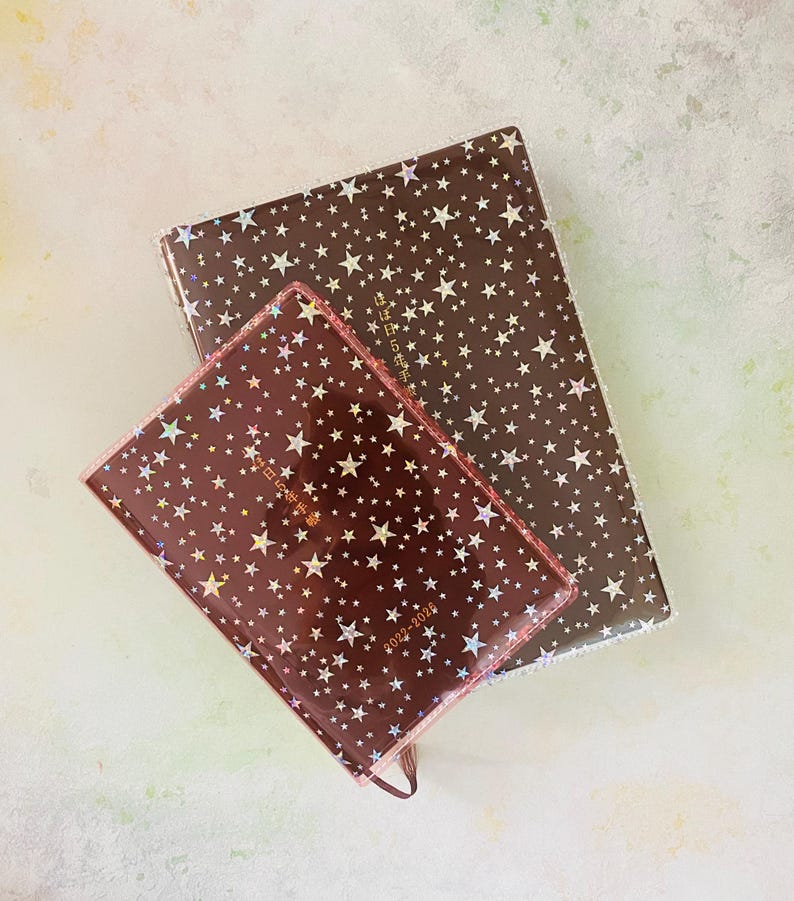 May include: Two brown star-patterned journals with gold lettering. The smaller journal has the text "2022-2025" on the cover.