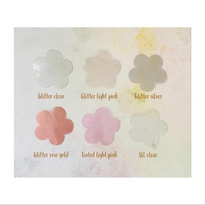 May include: Six flower-shaped samples of clear, glitter-infused resin in various colors, including clear, light pink, silver, rose gold, tinted light pink, and all clear. The samples are labeled with their corresponding names.