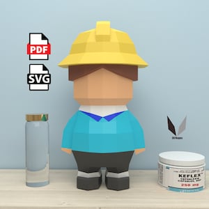 Könnte beinhalten: Ein 3D-Papiermodell eines Bauarbeiters mit gelbem Helm und blauem Hemd. Das Modell steht auf einer Holzoberfläche mit einer durchsichtigen Glasflasche und einer Medikamentenflasche.