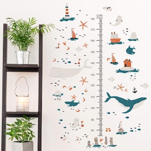 Pode incluir: Um decalque de parede lúdico com um gráfico de altura com ilustrações de tema náutico. Inclui um farol, veleiros, baleias, estrelas do mar e outras criaturas marinhas. O gráfico mede até 180 cm.