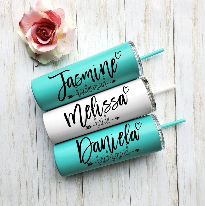 Pode incluir: Tr&ecirc;s copos turquesa e branco com texto preto e setas. Os copos s&atilde;o etiquetados como "Jasmine bridesmaid", "Melissa bride" e "Daniela bridesmaid".