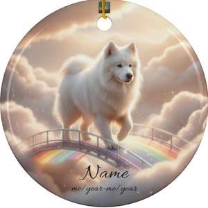 May include: A round ceramic ornament featuring a fluffy white dog walking across a rainbow bridge. The background depicts a cloudy sky with soft, warm tones. The ornament has a gold string for hanging, and the text "Name" and "mo/year-mo/year" are at the bottom.