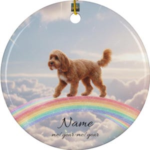 May include: A circular ceramic ornament with a brown dog on a rainbow, set against a cloudy sky. It has a gold hanging string and the text "Name" and "mol year-mo/ year".