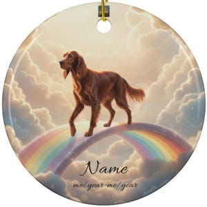 May include: A round ceramic ornament featuring a brown dog walking on a rainbow bridge against a cloudy sky. The ornament has a gold string for hanging and includes the text "Name" and "mo/year-mo/year".