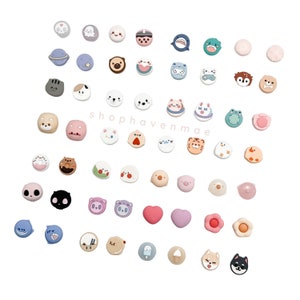 May include: A collection of colorful, round, silicone phone charms featuring various animal, food, and object designs. The charms are arranged in a circular pattern on a white background. The text "shophavenmae" is visible in the center of the image.