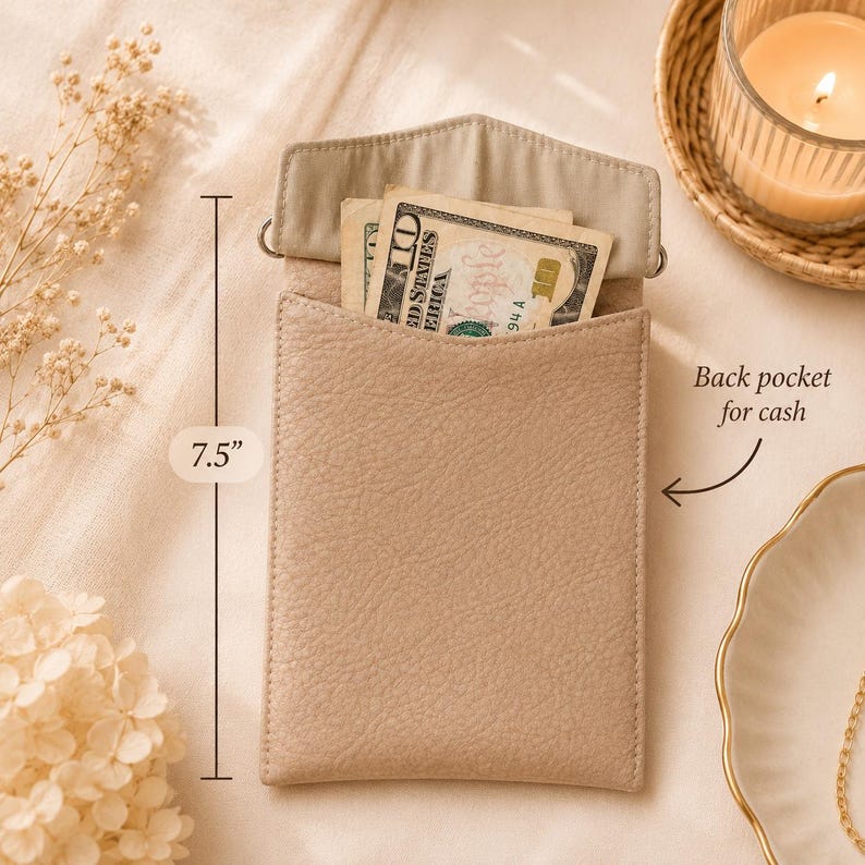 K&ouml;nnte beinhalten: Eine beigefarbene Tasche aus strukturiertem Leder mit Klappverschluss und einer R&uuml;ckentasche, in der ein Zehn-Dollar-Schein steckt. Die Tasche ist 19,05 cm hoch. Sie hat einen rechteckigen K&ouml;rper mit einer spitzen Klappe und hellem Innenfutter.