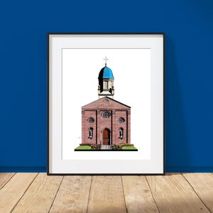 May include: A framed print featuring a red brick church with a prominent blue dome and a cross at the peak. The building has a central arched wooden door, circular windows, and small statues on either side of the entrance, set against a white background.