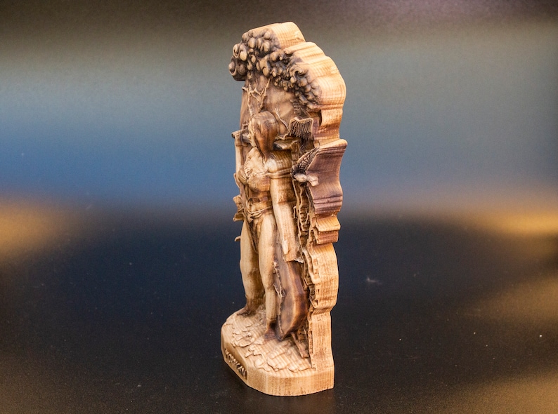 May include: A wooden sculpture of a woman standing in front of a tree. The sculpture is carved in detail and has a natural wood finish.