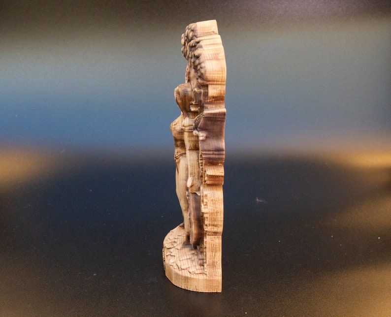 May include: A wooden wall sculpture of a woman standing with her arms raised, carved in a detailed style. The sculpture is made of light brown wood and has a natural finish.