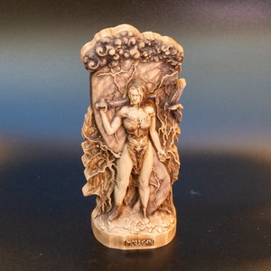 May include: A wooden sculpture of the Celtic goddess Morrigan, depicted as a warrior woman holding a sword and shield. The sculpture is carved with intricate details, including clouds, lightning bolts, and a raven.