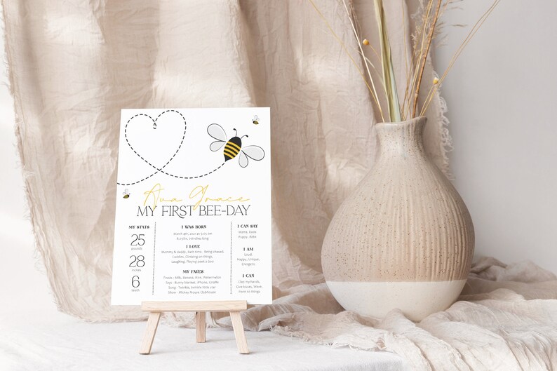 May include: A white printable first birthday sign with a bee theme. The sign says "Anna Grace My First Bee-Day" and includes details about the baby's first year, such as age, weight, and favorite things.