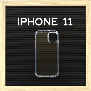 May include: Clear iPhone 11 case on a black background with the text "IPHONE 11" in white block letters. The case is transparent and has a protective design. The background is a textured, dark surface.