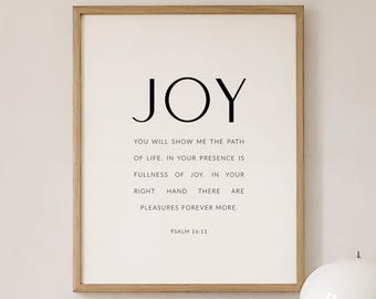 May include: A rectangular wall art print in a light wood frame featuring the word JOY in large black letters, followed by the text: YOU WILL SHOW ME THE PATH OF LIFE. IN YOUR PRESENCE IS FULLNESS OF JOY. IN YOUR RIGHT HAND THERE ARE PLEASURES FOREVER MORE. PSALM 16:11.
