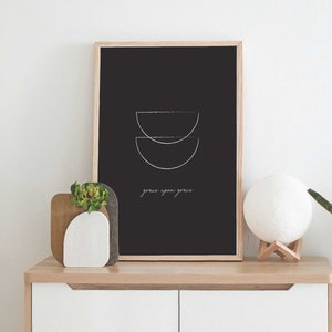 Puede incluir: Una impresi&oacute;n enmarcada en negro con un dise&ntilde;o minimalista de dos semic&iacute;rculos superpuestos en blanco. El texto "grace upon grace" est&aacute; escrito debajo del dise&ntilde;o.
