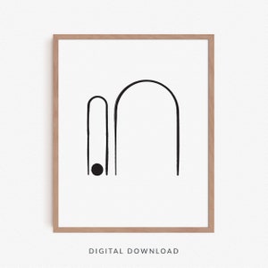 Pode incluir: Impressão de arte abstrata em preto e branco com dois arcos e um círculo. A impressão é emoldurada em uma moldura de madeira clara.
