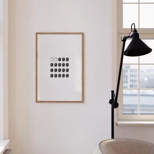 May include: A framed black and white print of a geometric design with a series of squares in varying shades of gray. The print is hanging on a white wall in a modern interior.