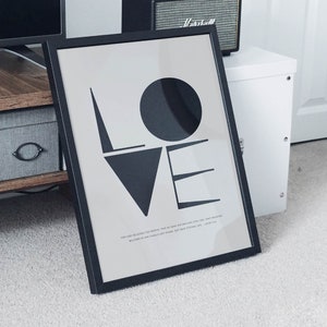 May include: A black framed print with the word "LOVE" in large, stylized black letters. The print includes a quote from the Bible: "For God so loved the world, that he gave his one and only Son, that whoever believes in him shall not perish but have eternal life." - John 3:16