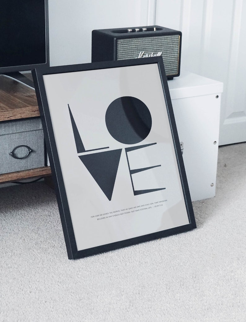 May include: A black framed print with the word "LOVE" in large, stylized black letters. The print includes a quote from the Bible: "For God so loved the world, that he gave his one and only Son, that whoever believes in him shall not perish but have eternal life." - John 3:16