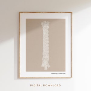 Op de afbeelding: Een ingelijste print met een beige achtergrond en een wit, gevlochten touwontwerp. De tekst "Een drievoudig koord breekt niet snel" staat onderaan. De woorden "DIGITALE DOWNLOAD" staan onderaan het frame.